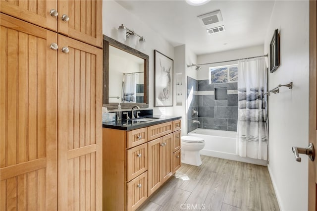 bathroom featuring toilet, wood finished floors, visible vents, vanity, and shower / tub combo with curtain