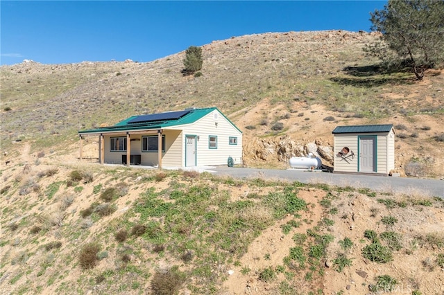 exterior space featuring a storage shed, a mountain view, solar panels, and an outdoor structure