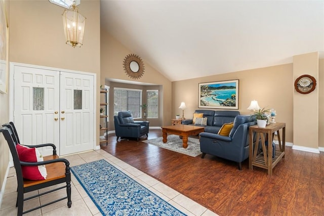 living area with baseboards, high vaulted ceiling, and wood finished floors