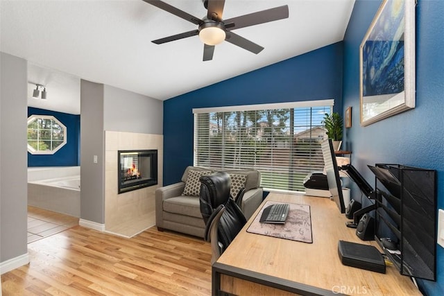 home office with a fireplace, lofted ceiling, plenty of natural light, and wood finished floors