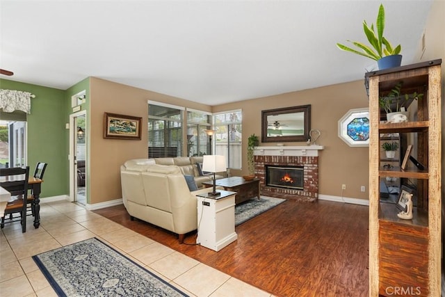 living area with a healthy amount of sunlight, a fireplace, baseboards, and wood finished floors