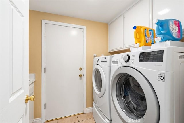 washroom with light tile patterned floors, cabinet space, and washer and clothes dryer