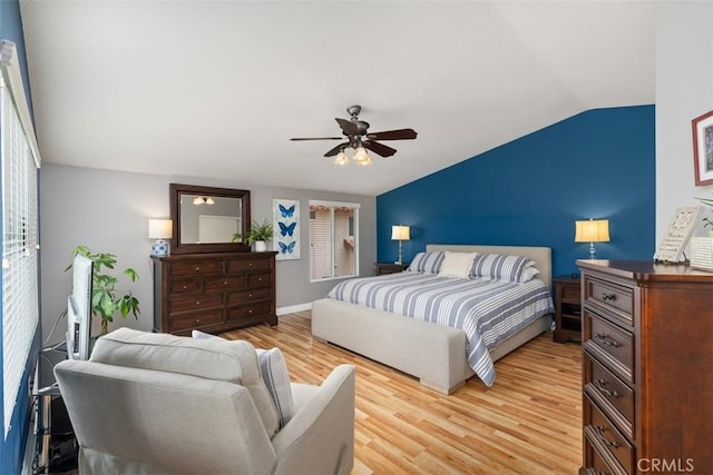 bedroom featuring light wood-type flooring, lofted ceiling, baseboards, and ceiling fan