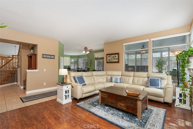 living room with baseboards, stairs, a ceiling fan, and wood finished floors