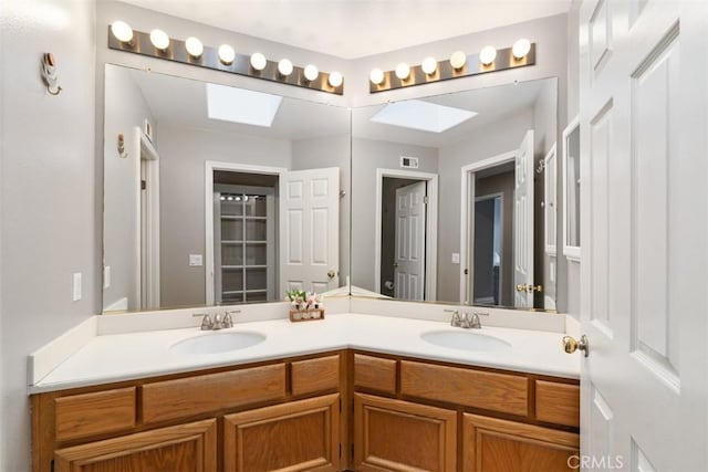 bathroom with double vanity, a skylight, and a sink