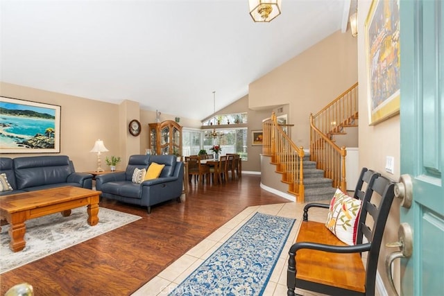 living area featuring stairway, wood finished floors, baseboards, and high vaulted ceiling