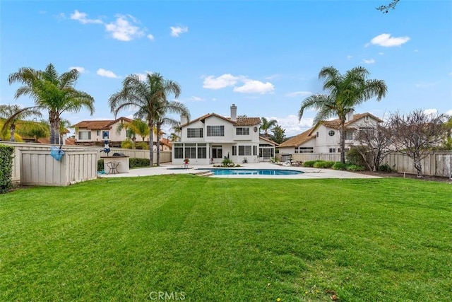 rear view of house with a patio, a fenced backyard, a yard, a sunroom, and a fenced in pool