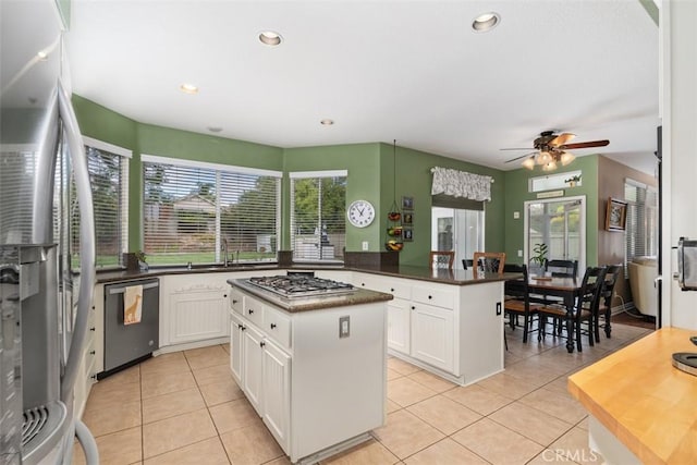 kitchen featuring a kitchen island, ceiling fan, light tile patterned floors, appliances with stainless steel finishes, and a peninsula