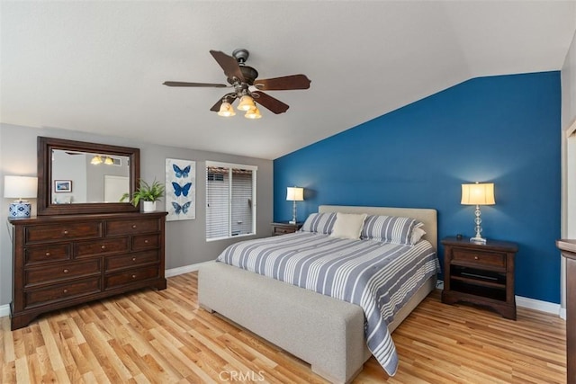 bedroom featuring light wood finished floors, ceiling fan, baseboards, and vaulted ceiling