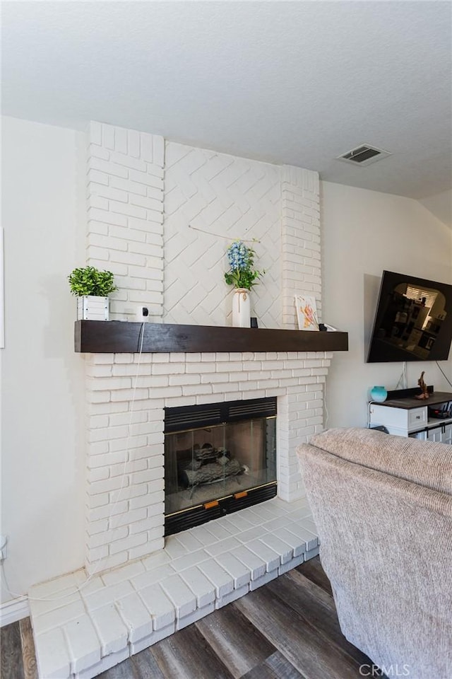 room details featuring a fireplace, wood finished floors, and visible vents