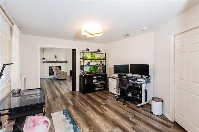 office area featuring visible vents, radiator, dark wood-style flooring, and a fireplace