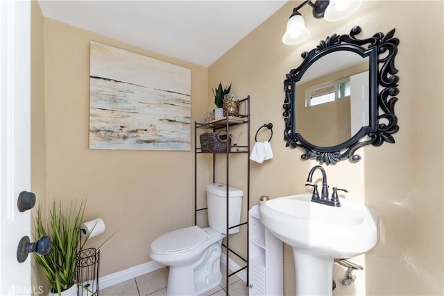 bathroom featuring tile patterned flooring, toilet, baseboards, and a sink