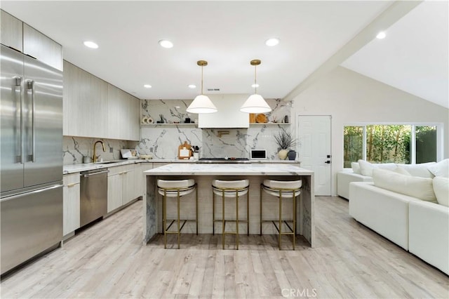 kitchen with modern cabinets, a sink, backsplash, stainless steel appliances, and a breakfast bar area