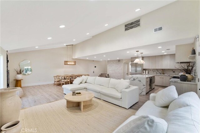 living room with recessed lighting, light wood-style floors, visible vents, and high vaulted ceiling