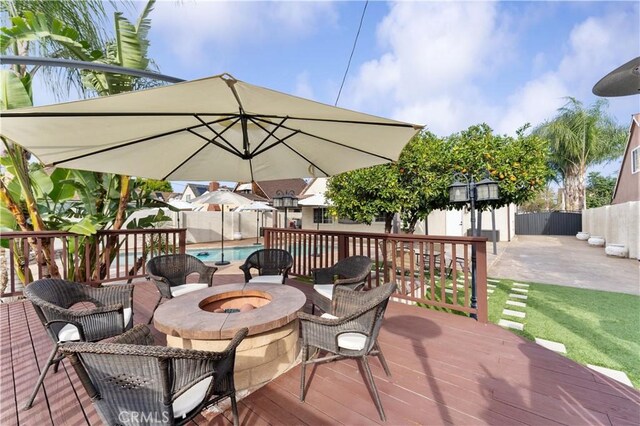 deck featuring a fenced in pool, a fire pit, a fenced backyard, and an outdoor structure