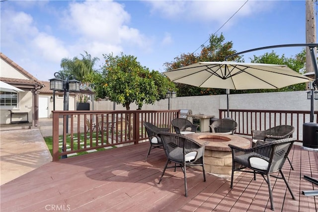 deck featuring an outdoor fire pit and fence