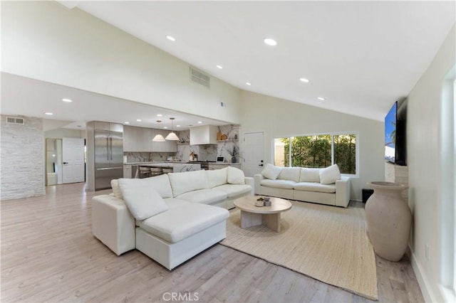 living area with recessed lighting, visible vents, light wood-style flooring, and high vaulted ceiling