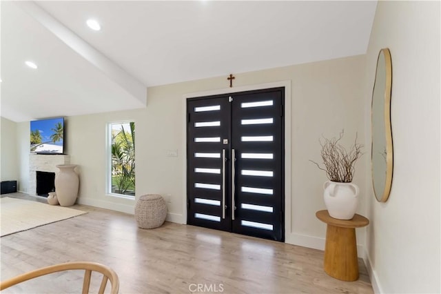 entryway featuring a fireplace, baseboards, and wood finished floors