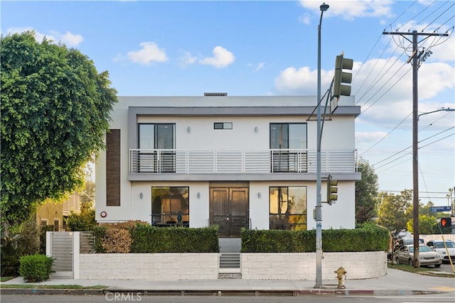 view of front of home featuring stucco siding and a balcony