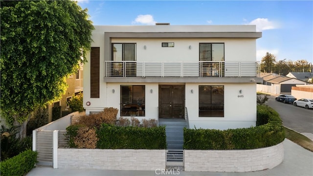 view of front of home with stucco siding and a balcony