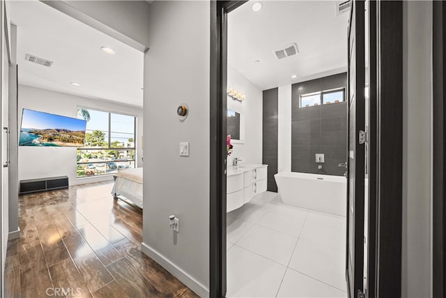 bathroom with a freestanding tub, visible vents, and vanity