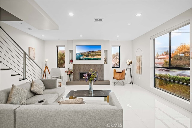 living room with recessed lighting, visible vents, a wealth of natural light, and a tile fireplace