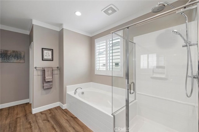 bathroom with wood finished floors, baseboards, a stall shower, crown molding, and a bath
