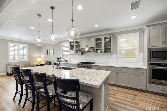 kitchen featuring visible vents, gray cabinetry, stainless steel appliances, and a sink