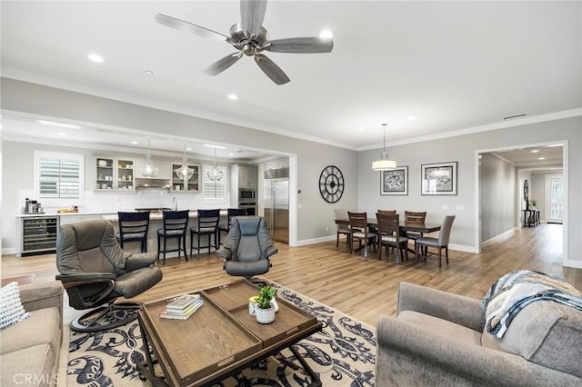 living room with visible vents, crown molding, beverage cooler, light wood-style floors, and a ceiling fan