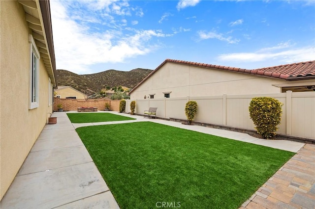 view of yard with a patio area, a fenced backyard, and a mountain view