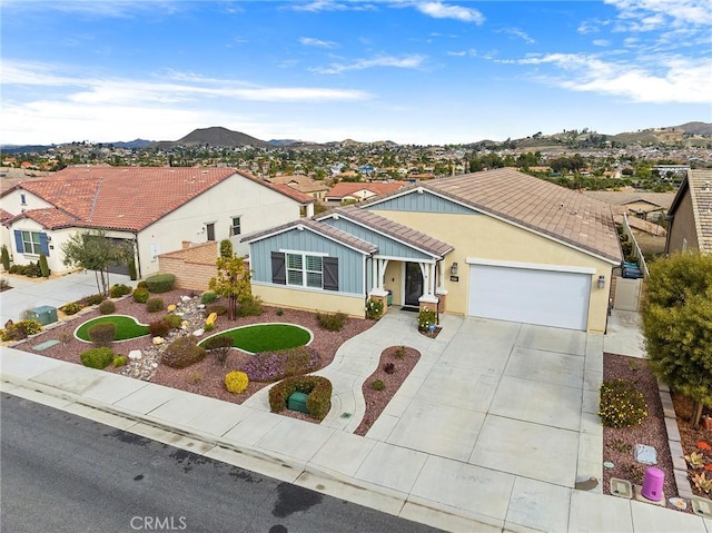 single story home with an attached garage, a residential view, stucco siding, driveway, and a mountain view