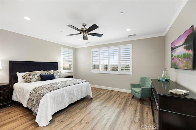 bedroom with visible vents, baseboards, ornamental molding, light wood-style flooring, and a ceiling fan