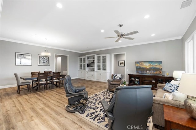 living area featuring crown molding, a ceiling fan, visible vents, and light wood finished floors