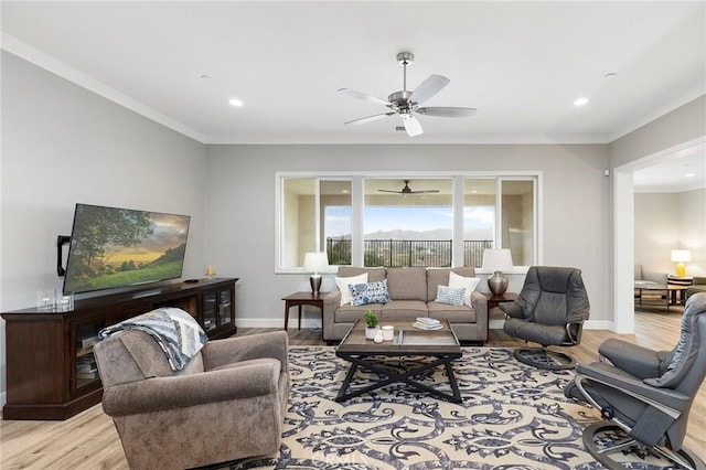 living room with crown molding, light wood-style floors, baseboards, and ceiling fan