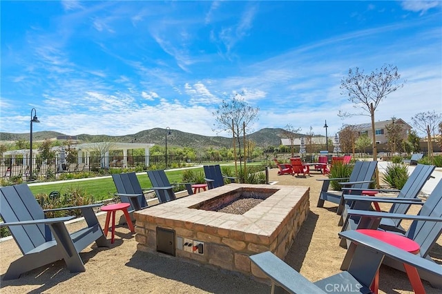 view of patio / terrace featuring fence, a mountain view, and an outdoor fire pit