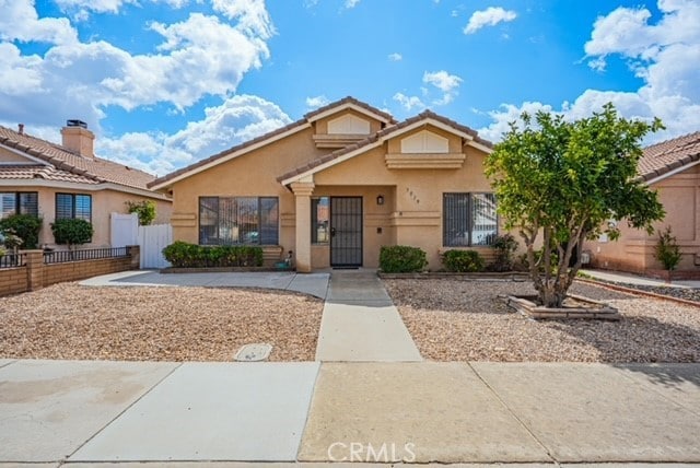 view of front of house with a tiled roof, a gate, fence, and stucco siding