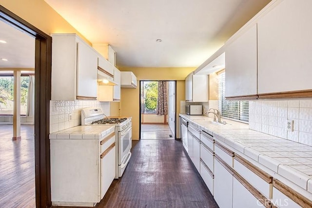 kitchen with tile countertops, white appliances, white cabinetry, and a sink