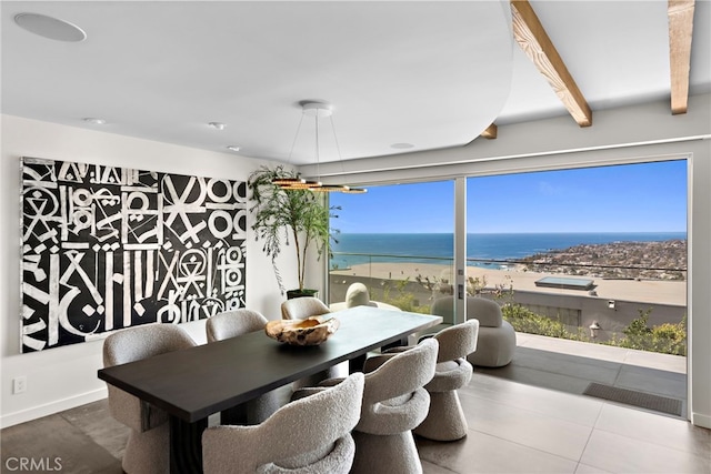 dining room featuring beamed ceiling and a water view