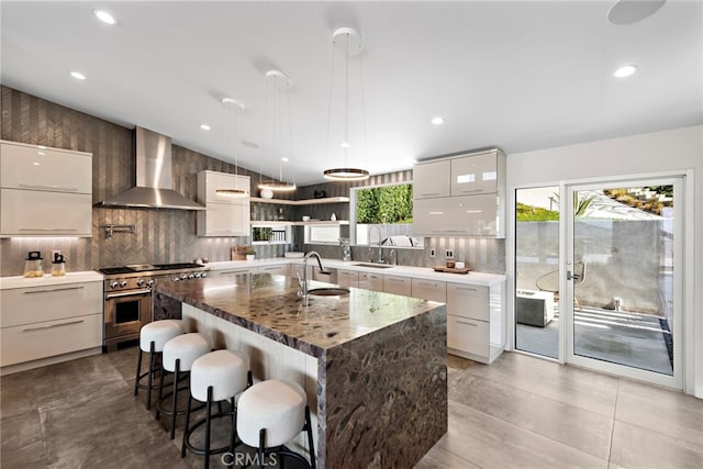 kitchen with double oven range, a sink, wall chimney exhaust hood, modern cabinets, and a wealth of natural light