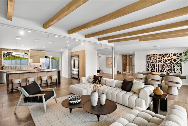 living room featuring rail lighting, lofted ceiling with beams, and baseboards