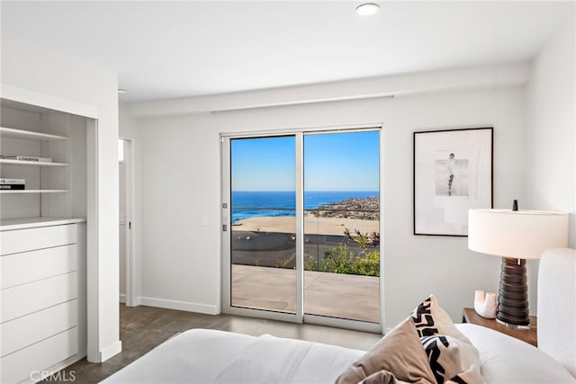 bedroom with access to outside, wood finished floors, baseboards, and a water view