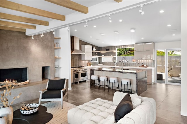 living room with a premium fireplace, lofted ceiling with beams, dark tile patterned flooring, recessed lighting, and track lighting