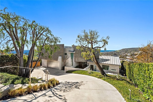 view of front of home featuring fence, stucco siding, metal roof, driveway, and a standing seam roof