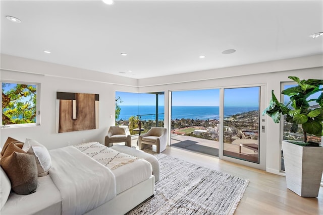 bedroom featuring recessed lighting, light wood-style flooring, a water view, and access to outside