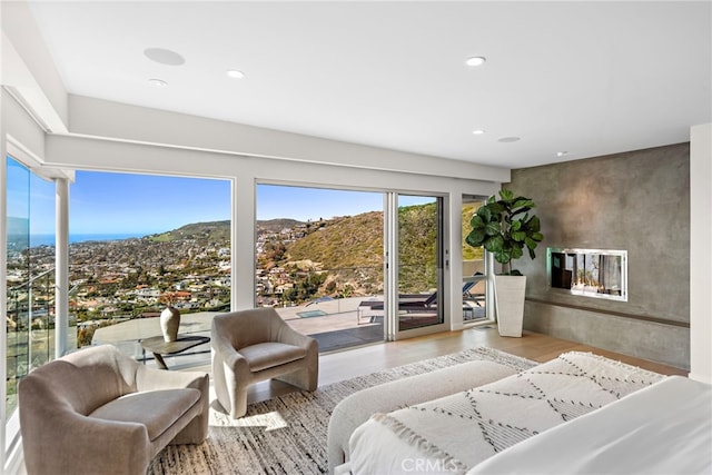 bedroom featuring access to exterior, an accent wall, recessed lighting, a fireplace, and wood finished floors