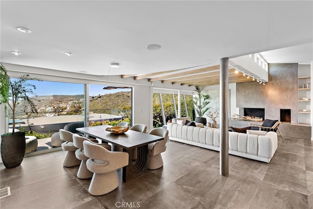 dining space with beam ceiling, built in features, a fireplace, and visible vents