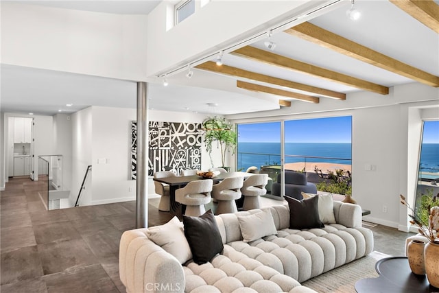 living room with beamed ceiling, a water view, baseboards, and rail lighting