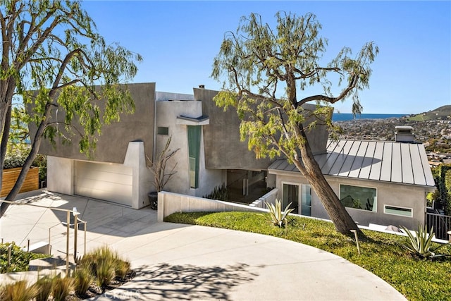 view of front of property with stucco siding, driveway, a standing seam roof, metal roof, and a chimney