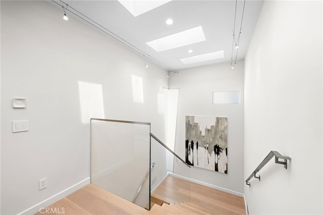 staircase featuring a skylight, recessed lighting, wood finished floors, and baseboards