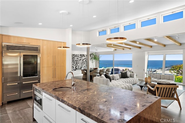 kitchen with a sink, stainless steel microwave, modern cabinets, and light brown cabinets